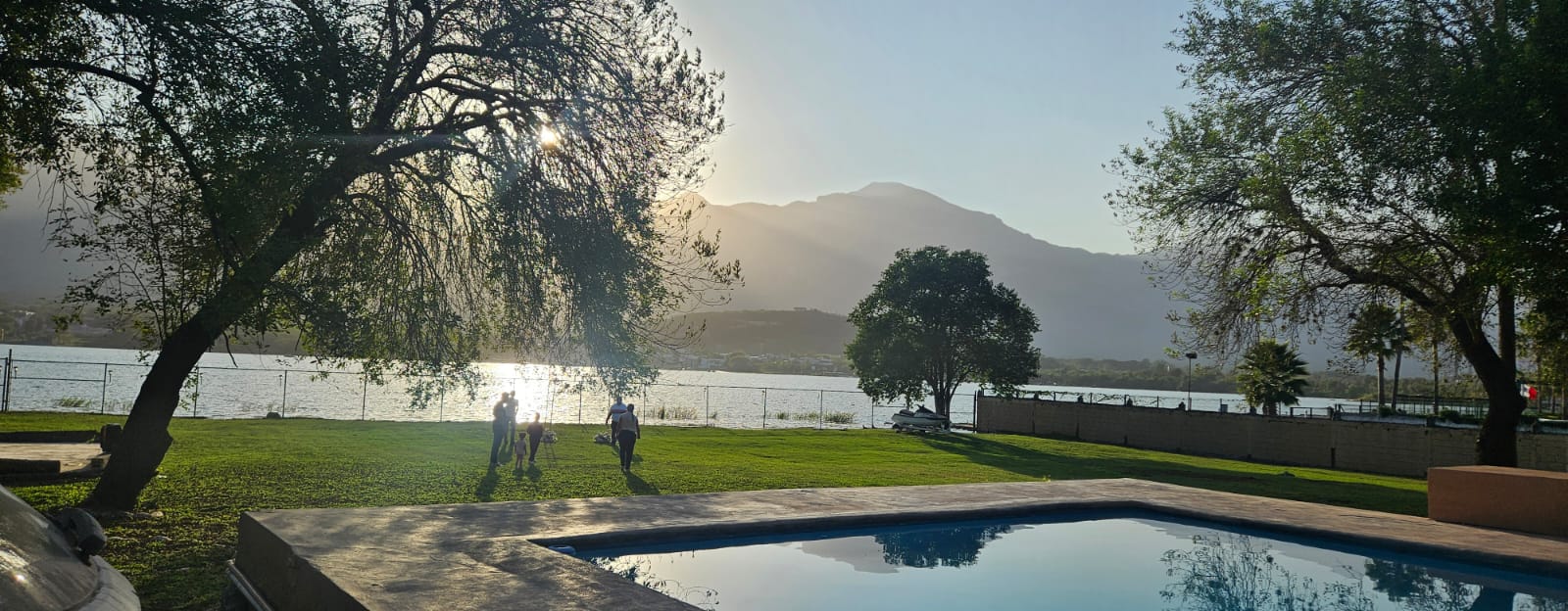 Quinta Paraiso donde se ve parte de la alberca, el jardín en el cual se ve conviviendo a una Familia y la presa de la boca